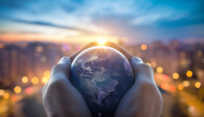 Planet Earth in the hands of a man against the background of the lights of the evening city. Concept and symbol on the theme of ecology, earth conservation. Elements of this image furnished by NASA.