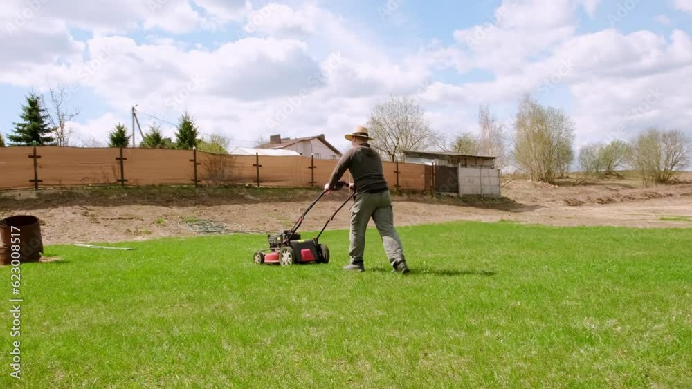 Lawn mowing. The gardener mows green grass. Cultivation. Garden care. Big field. Side view. Summer gardening. Backyard. Roll lawn growing. Electric lawn mower. Petrol self-propelled lawn mower. Lawn mowing. The gardener mows green grass. Cultivation. Garden care. Big field. Side view. Summer gardening. Backyard. Roll lawn growing. Electric lawn mower. Petrol self-propelled lawn mower.
