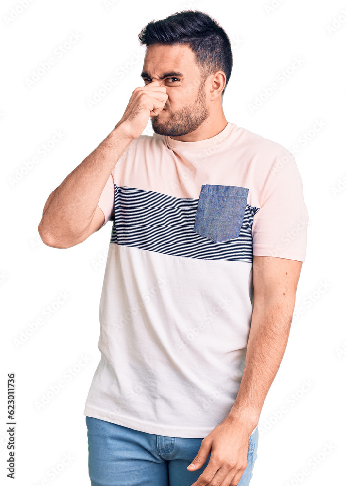 Young handsome man wearing casual clothes smelling something stinky and disgusting, intolerable smell, holding breath with fingers on nose. bad smell Young handsome man wearing casual clothes smelling something stinky and disgusting, intolerable smell, holding breath with fingers on nose. bad smell