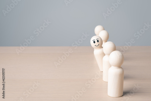 Introvert, Individuality Person. Unique man happy and enjoy isolation. Separation or Solitude person. Wooden figure with happy face split line from the crowd. Volunteer and sacrifice people concept.