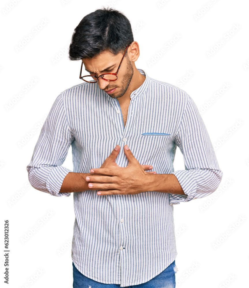 Young handsome man wearing casual clothes and glasses with hand on stomach because indigestion, painful illness feeling unwell. ache concept. Young handsome man wearing casual clothes and glasses with hand on stomach because indigestion, painful illness feeling unwell. ache concept.