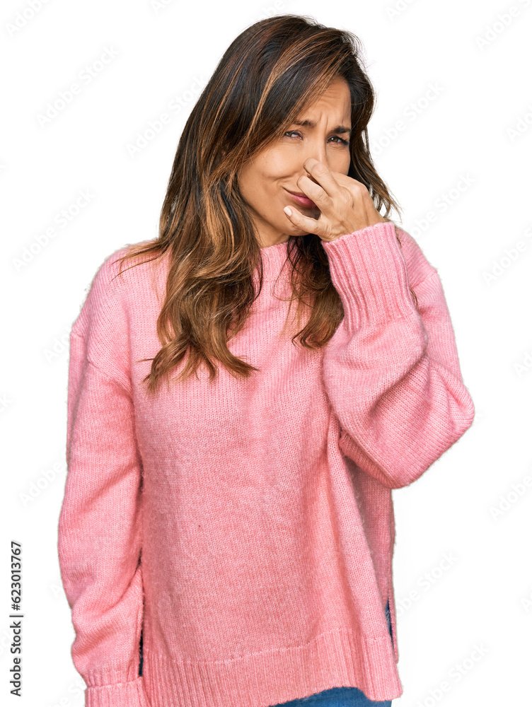 Young hispanic woman wearing casual clothes smelling something stinky and disgusting, intolerable smell, holding breath with fingers on nose. bad smell