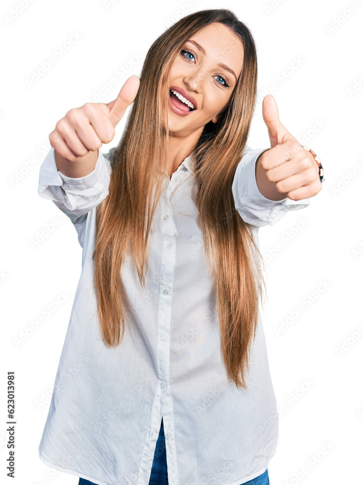 Beautiful caucasian woman wearing casual white shirt approving doing positive gesture with hand, thumbs up smiling and happy for success. winner gesture. Beautiful caucasian woman wearing casual white shirt approving doing positive gesture with hand, thumbs up smiling and happy for success. winner gesture.