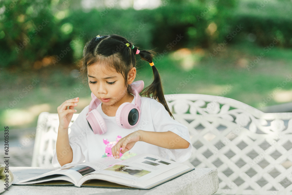 Little asian girl reading a book in the garden. Education concept. Little asian girl reading a book in the garden. Education concept.