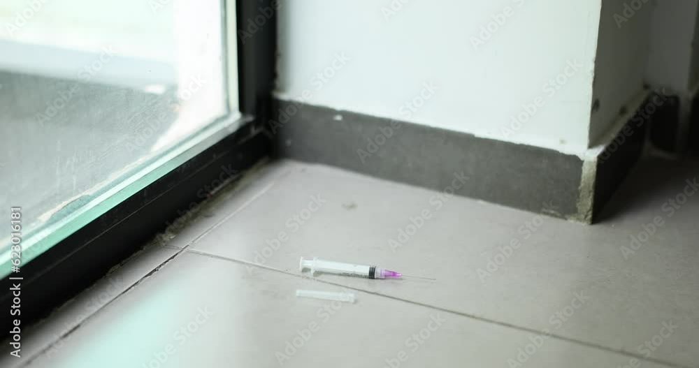 Used medical syringe with needle was thrown on floor. Disposal of