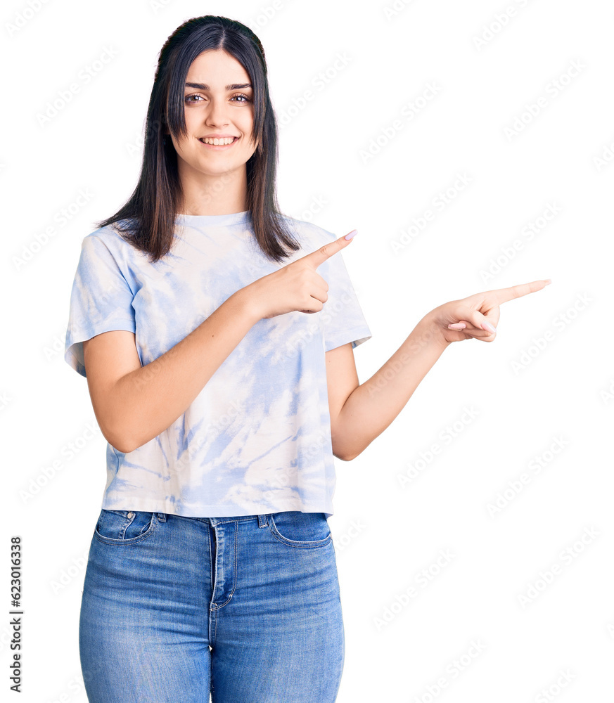 Young beautiful girl wearing casual t shirt smiling and looking at the camera pointing with two hands and fingers to the side. Young beautiful girl wearing casual t shirt smiling and looking at the camera pointing with two hands and fingers to the side.