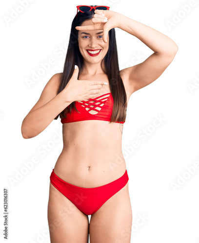 Young beautiful caucasian woman wearing bikini smiling making frame with hands and fingers with happy face. creativity and photography concept. © Krakenimages.com