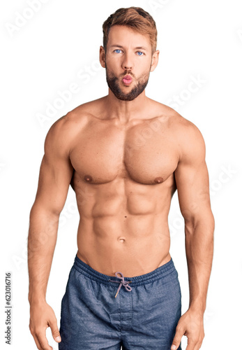 Young caucasian man standing shirtless making fish face with lips, crazy and comical gesture. funny expression.