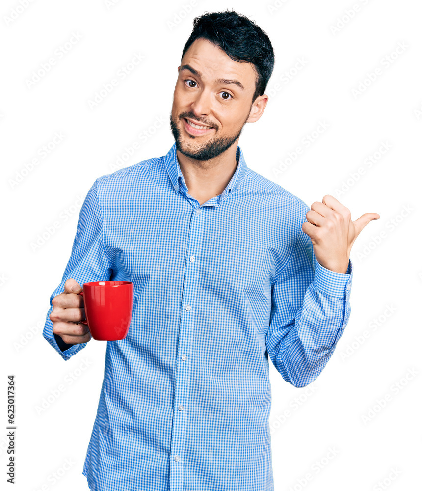 Hispanic man with beard drinking a cup coffee pointing thumb up to the side smiling happy with open mouth Hispanic man with beard drinking a cup coffee pointing thumb up to the side smiling happy with open mouth