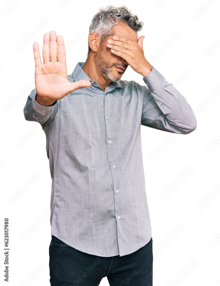 Middle age grey-haired man wearing casual clothes covering eyes with hands and doing stop gesture with sad and fear expression. embarrassed and negative concept. Middle age grey-haired man wearing casual clothes covering eyes with hands and doing stop gesture with sad and fear expression. embarrassed and negative concept.