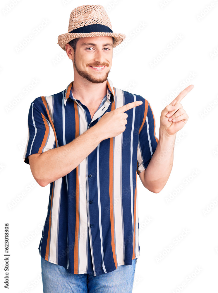 Young handsome caucasian man wearing summer hat smiling and looking at the camera pointing with two hands and fingers to the side. Young handsome caucasian man wearing summer hat smiling and looking at the camera pointing with two hands and fingers to the side.