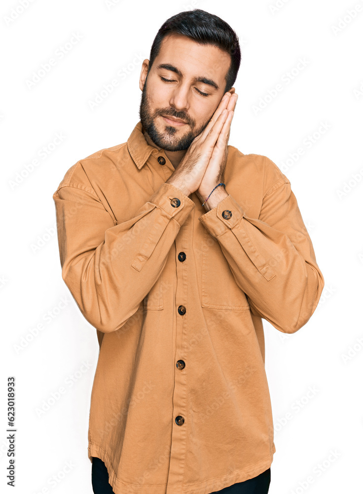 Young hispanic man wearing casual clothes sleeping tired dreaming and posing with hands together while smiling with closed eyes. Young hispanic man wearing casual clothes sleeping tired dreaming and posing with hands together while smiling with closed eyes.