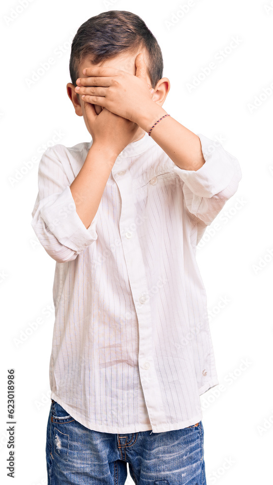 Cute blond kid wearing elegant shirt covering eyes and mouth with hands, surprised and shocked. hiding emotion Cute blond kid wearing elegant shirt covering eyes and mouth with hands, surprised and shocked. hiding emotion