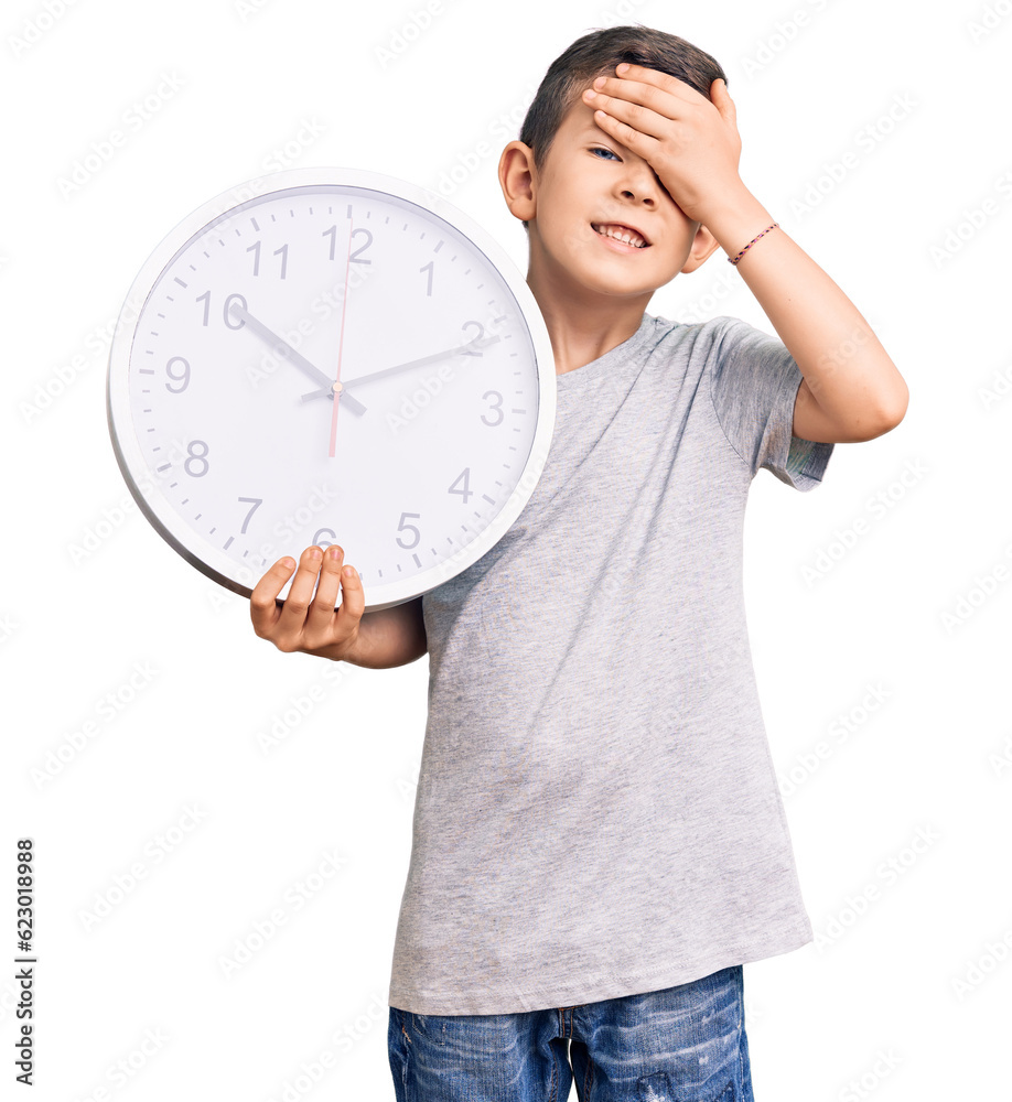 Cute blond kid holding big clock stressed and frustrated with hand on head, surprised and angry face Cute blond kid holding big clock stressed and frustrated with hand on head, surprised and angry face