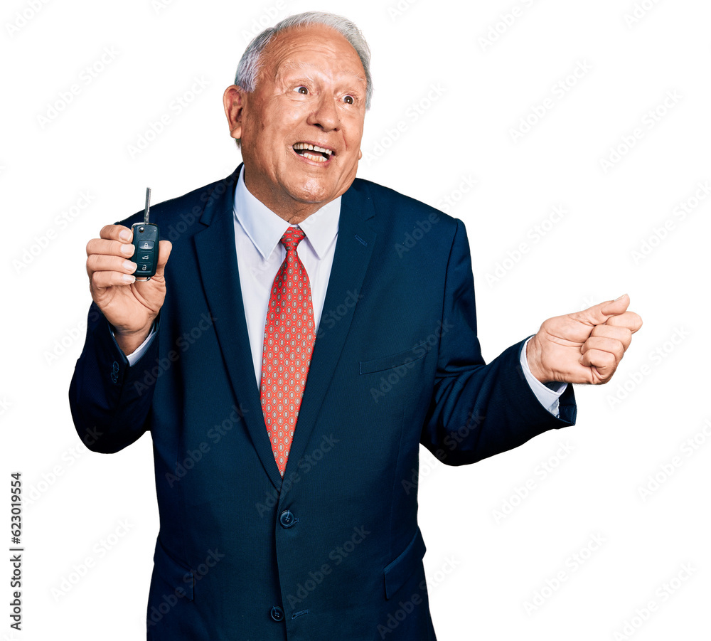 Senior business man with grey hair holding key of new car screaming proud, celebrating victory and success very excited with raised arm Senior business man with grey hair holding key of new car screaming proud, celebrating victory and success very excited with raised arm