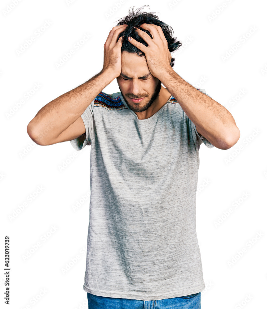 Naklejka premium Young hispanic man wearing casual t shirt suffering from headache desperate and stressed because pain and migraine. hands on head.