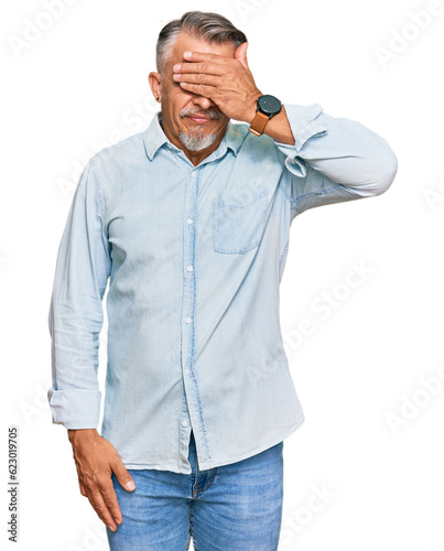 Middle age grey-haired man wearing casual clothes covering eyes with hand, looking serious and sad. sightless, hiding and rejection concept © Krakenimages.com