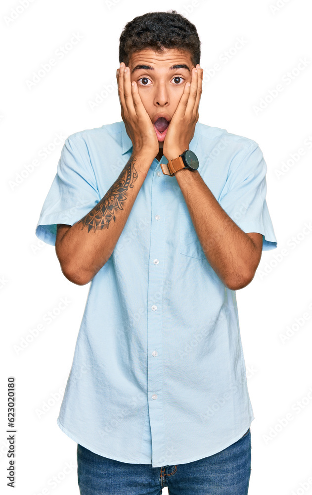 Young handsome african american man wearing casual clothes afraid and shocked, surprise and amazed expression with hands on face Young handsome african american man wearing casual clothes afraid and shocked, surprise and amazed expression with hands on face