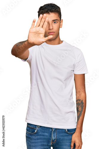 Young handsome african american man wearing casual white tshirt doing stop sing with palm of the hand. warning expression with negative and serious gesture on the face.