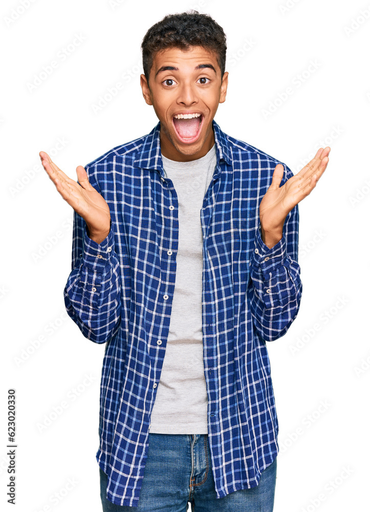 Young handsome african american man wearing casual clothes celebrating crazy and amazed for success with arms raised and open eyes screaming excited. winner concept Young handsome african american man wearing casual clothes celebrating crazy and amazed for success with arms raised and open eyes screaming excited. winner concept