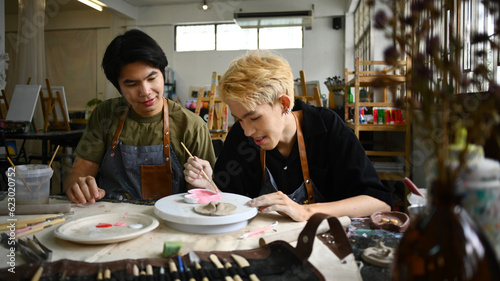 Joyful young asian man are creating handmade ceramics  shaping and decorating pottery in workshop