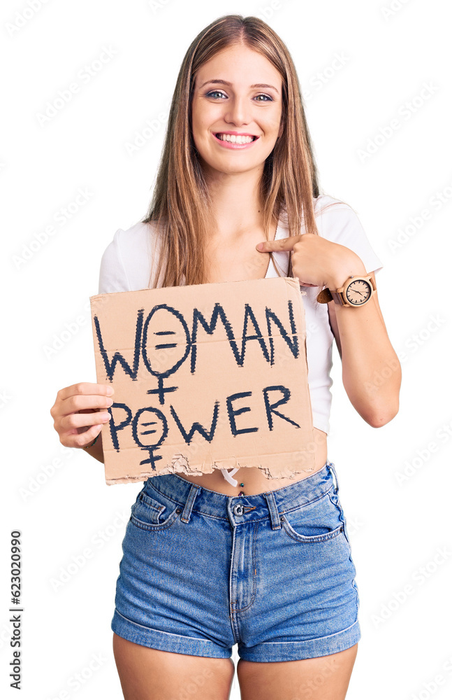 Young beautiful blonde woman holding woman power banner pointing finger to one self smiling happy and proud Young beautiful blonde woman holding woman power banner pointing finger to one self smiling happy and proud