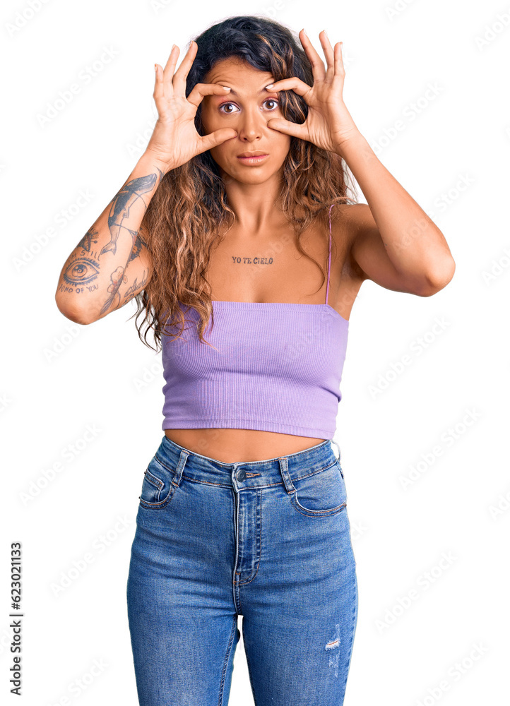 Young hispanic woman with tattoo wearing casual clothes trying to open eyes with fingers, sleepy and tired for morning fatigue Young hispanic woman with tattoo wearing casual clothes trying to open eyes with fingers, sleepy and tired for morning fatigue
