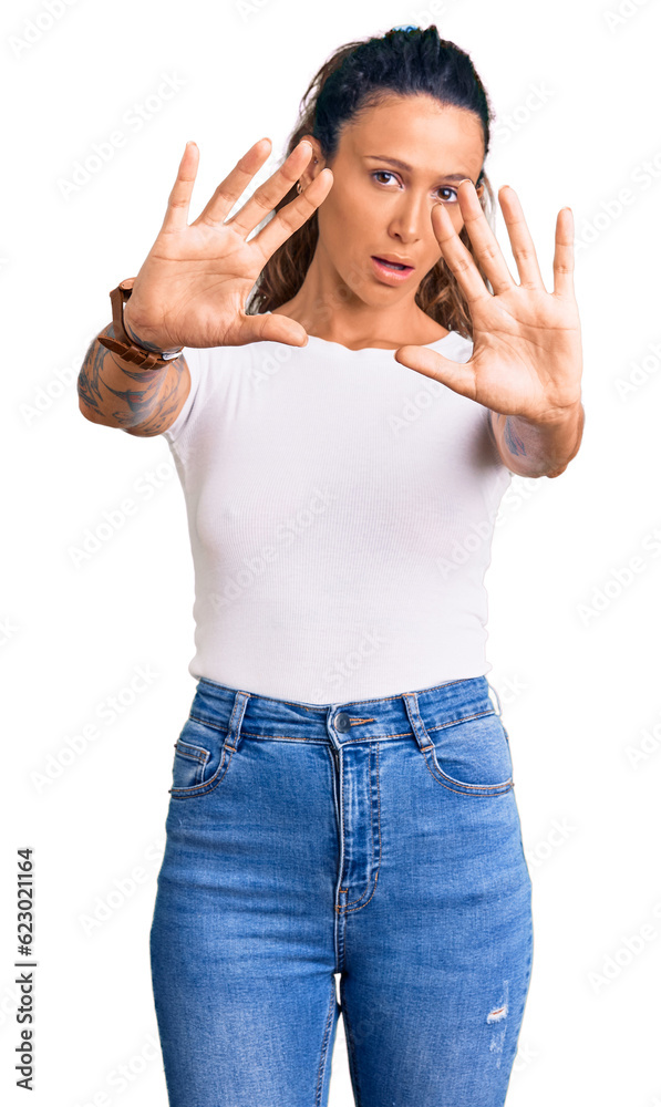 Young hispanic woman with tattoo wearing casual white tshirt doing frame using hands palms and fingers, camera perspective