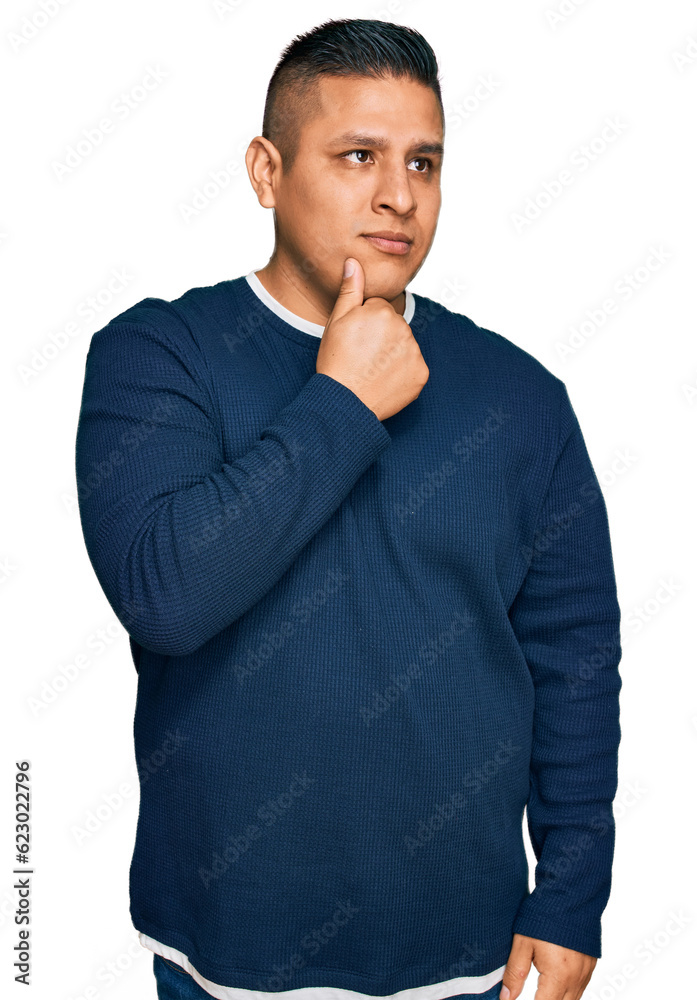 Young latin man wearing casual clothes with hand on chin thinking about question, pensive expression. smiling with thoughtful face. doubt concept. Young latin man wearing casual clothes with hand on chin thinking about question, pensive expression. smiling with thoughtful face. doubt concept.