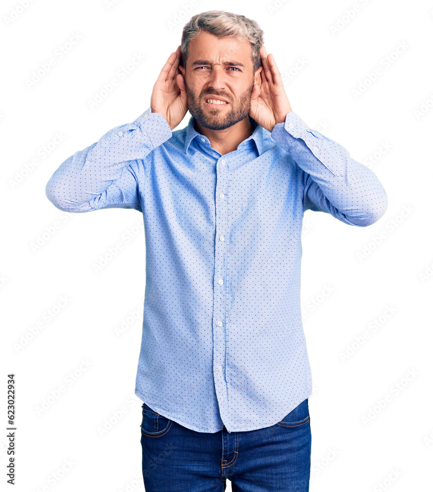 Young handsome blond man wearing elegant shirt trying to hear both hands on ear gesture, curious for gossip. hearing problem, deaf Young handsome blond man wearing elegant shirt trying to hear both hands on ear gesture, curious for gossip. hearing problem, deaf