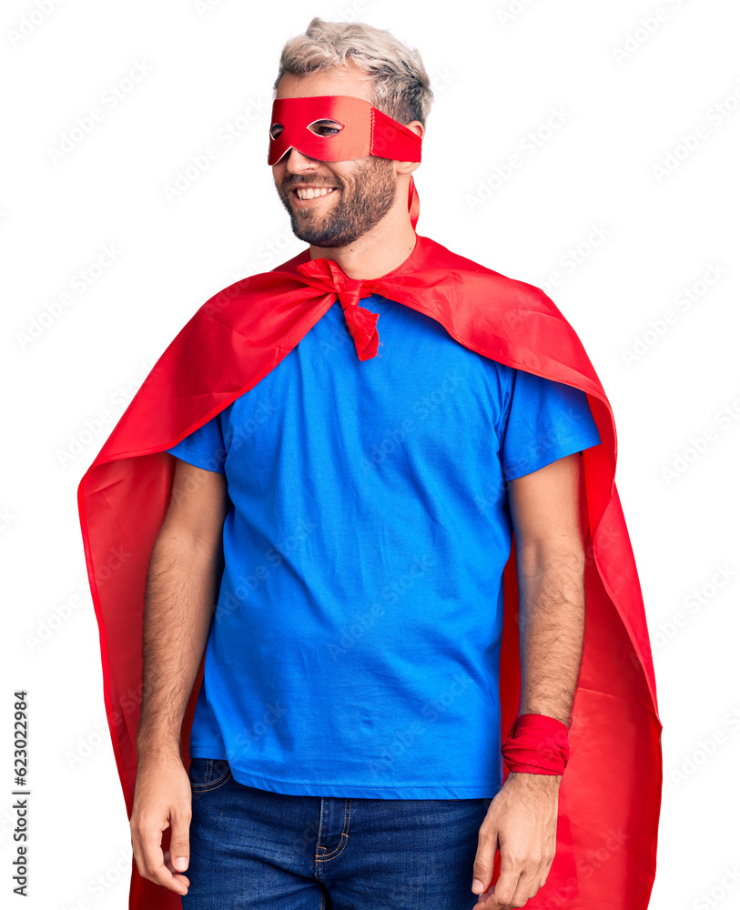 Young blond man wearing super hero custome looking away to side with smile on face, natural expression. laughing confident. Young blond man wearing super hero custome looking away to side with smile on face, natural expression. laughing confident.