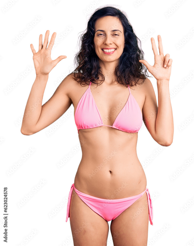 Young beautiful hispanic woman wearing bikini showing and pointing up with fingers number eight while smiling confident and happy. Young beautiful hispanic woman wearing bikini showing and pointing up with fingers number eight while smiling confident and happy.
