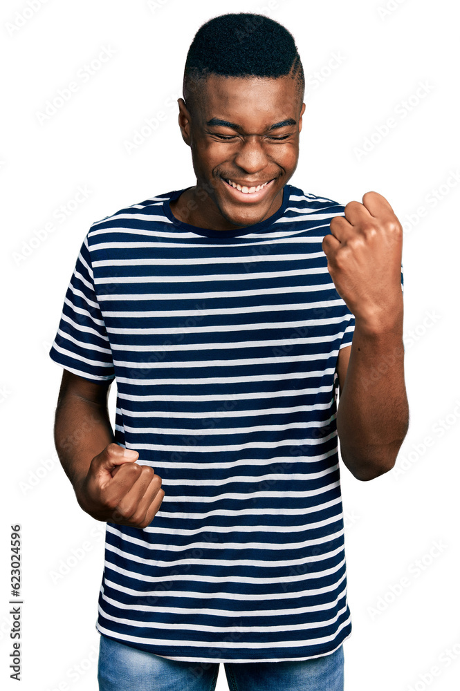 Young african american man wearing casual striped t shirt celebrating surprised and amazed for success with arms raised and eyes closed Young african american man wearing casual striped t shirt celebrating surprised and amazed for success with arms raised and eyes closed