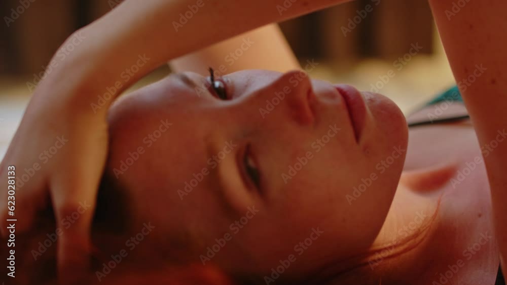 Close up of a beautiful young woman lying in bed and looking at camera Close up of a beautiful young woman lying in bed and looking at camera