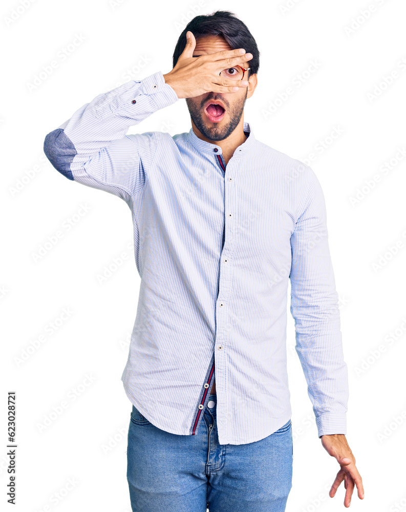 Handsome hispanic man wearing business shirt and glasses peeking in shock covering face and eyes with hand, looking through fingers with embarrassed expression. Handsome hispanic man wearing business shirt and glasses peeking in shock covering face and eyes with hand, looking through fingers with embarrassed expression.