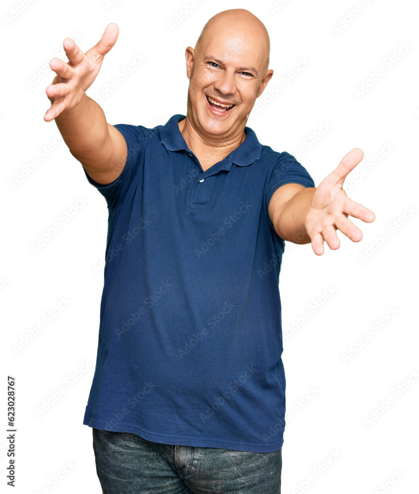 Middle age bald man wearing casual clothes looking at the camera smiling with open arms for hug. cheerful expression embracing happiness. Middle age bald man wearing casual clothes looking at the camera smiling with open arms for hug. cheerful expression embracing happiness.