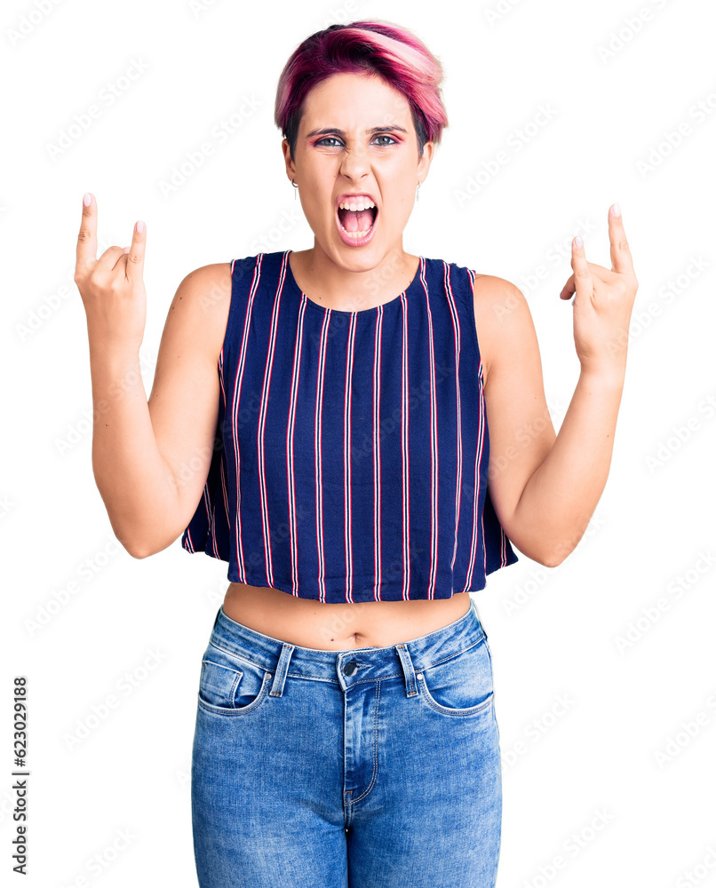 Young beautiful woman with pink hair wearing casual clothes shouting with crazy expression doing rock symbol with hands up. music star. heavy concept. Young beautiful woman with pink hair wearing casual clothes shouting with crazy expression doing rock symbol with hands up. music star. heavy concept.