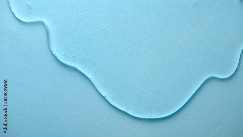 Cosmetics serum fluid gel flowing over blue background, hyaluronic acid cream texture, facial treatment, Cream gel transparent cosmetic serum oil texture backdrop, hydrating, moisturizing. Slow motion