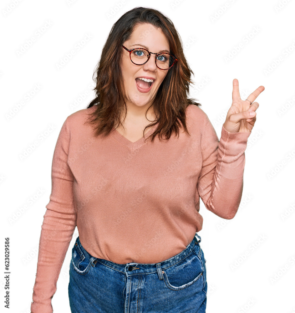 Young plus size woman wearing casual clothes and glasses smiling with happy face winking at the camera doing victory sign with fingers. number two. Young plus size woman wearing casual clothes and glasses smiling with happy face winking at the camera doing victory sign with fingers. number two.