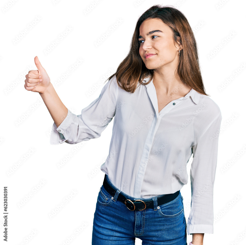 Young caucasian girl wearing casual white shirt looking proud, smiling doing thumbs up gesture to the side Young caucasian girl wearing casual white shirt looking proud, smiling doing thumbs up gesture to the side