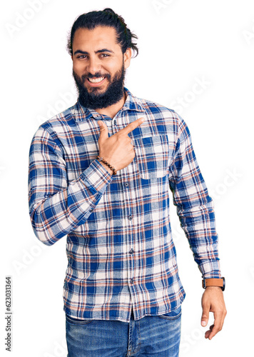 Young arab man wearing casual clothes cheerful with a smile of face pointing with hand and finger up to the side with happy and natural expression on face