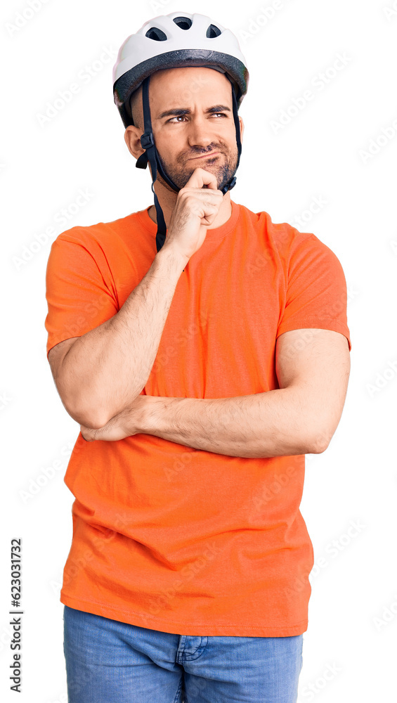 Young handsome man wearing bike helmet serious face thinking about question with hand on chin, thoughtful about confusing idea Young handsome man wearing bike helmet serious face thinking about question with hand on chin, thoughtful about confusing idea
