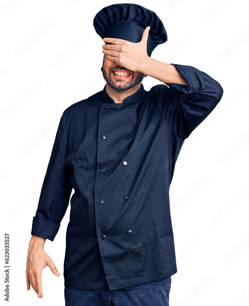 Young hispanic man wearing cooker uniform smiling and laughing with hand on face covering eyes for surprise. blind concept.