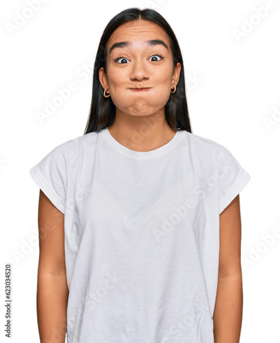 фотографія Young asian woman wearing casual white t shirt puffing cheeks with funny face