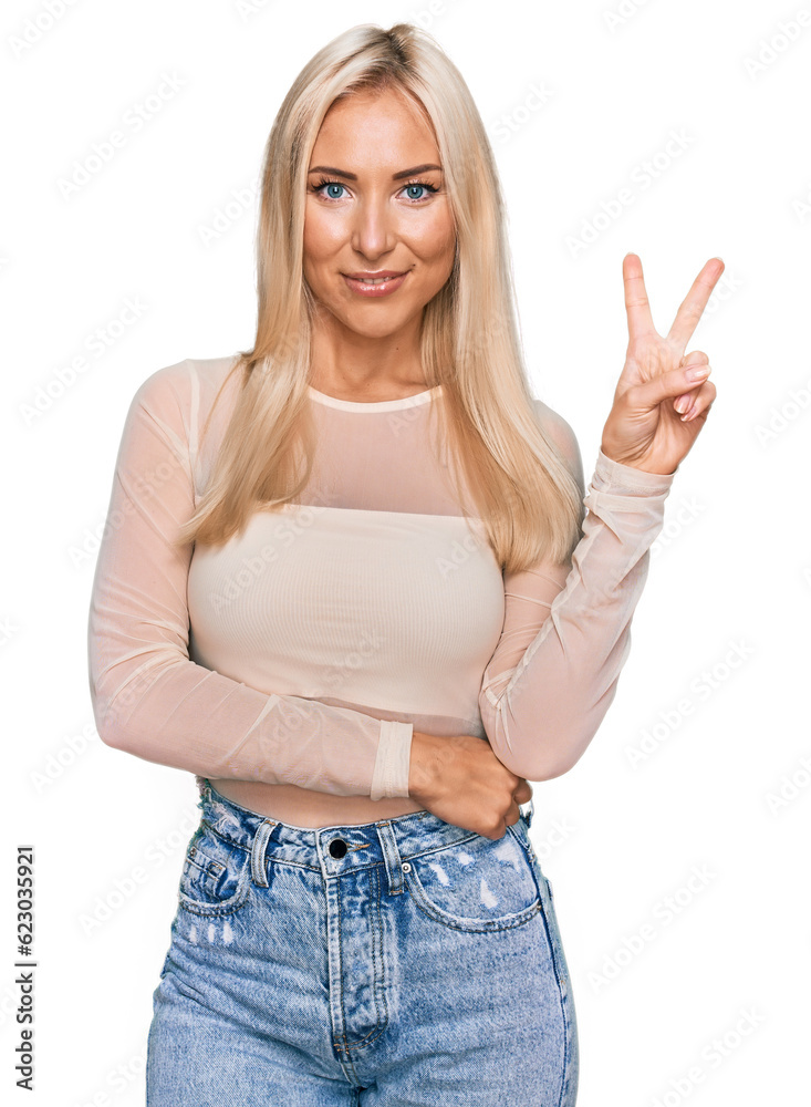 Young blonde woman wearing casual clothes smiling with happy face winking at the camera doing victory sign. number two. Young blonde woman wearing casual clothes smiling with happy face winking at the camera doing victory sign. number two.