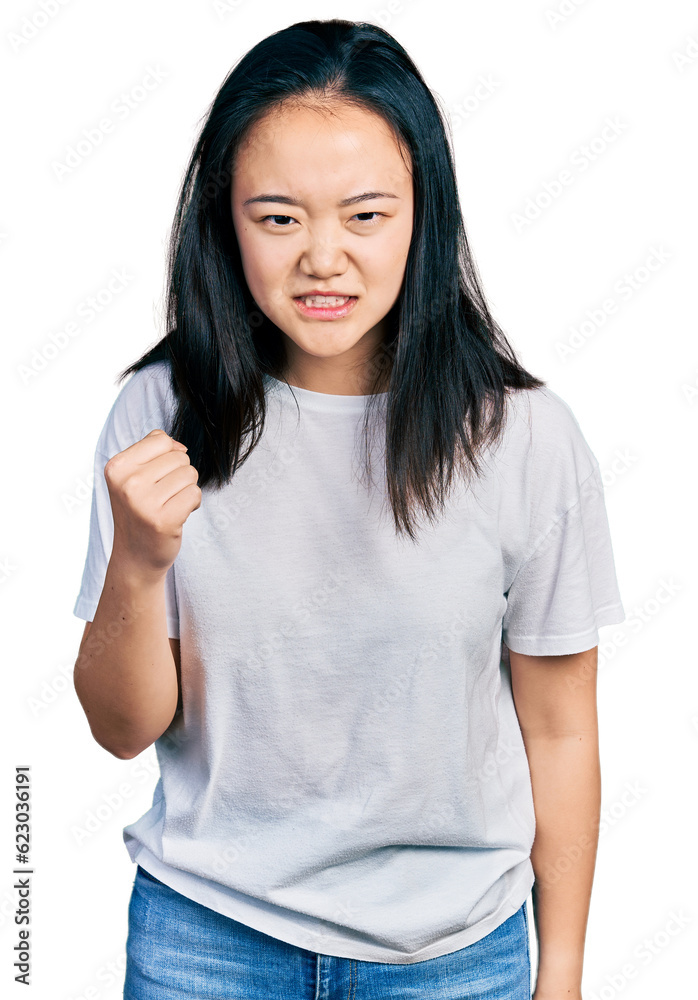 Young chinese woman wearing casual white t shirt angry and mad raising fist frustrated and furious while shouting with anger. rage and aggressive concept. Young chinese woman wearing casual white t shirt angry and mad raising fist frustrated and furious while shouting with anger. rage and aggressive concept.