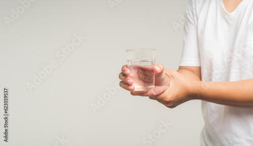 Parkinson's disease. Close-up of hands trying to hold a glass of water.