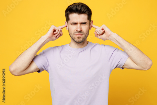 Young sad caucasian man he wear light purple t-shirt casual clothes cover ears with hands fingers do not want to listen scream isolated on plain yellow background studio portrait. Lifestyle concept. © ViDi Studio