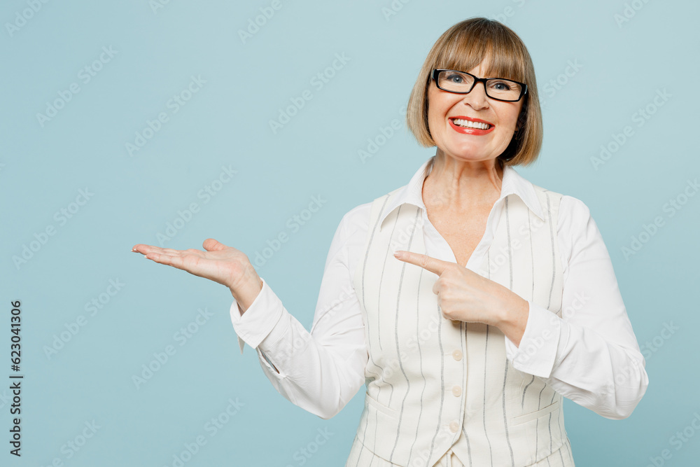 Blonde employee business woman 50s wear white classic suit glasses formal clothes point index finger on empty palm with area isolated on plain pastel light blue background. Achievement career concept. Blonde employee business woman 50s wear white classic suit glasses formal clothes point index finger on empty palm with area isolated on plain pastel light blue background. Achievement career concept.