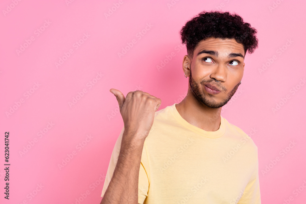 Photo of nice interested guy direct finger empty space look unsure have doubts wear shirt isolated pink color background Photo of nice interested guy direct finger empty space look unsure have doubts wear shirt isolated pink color background